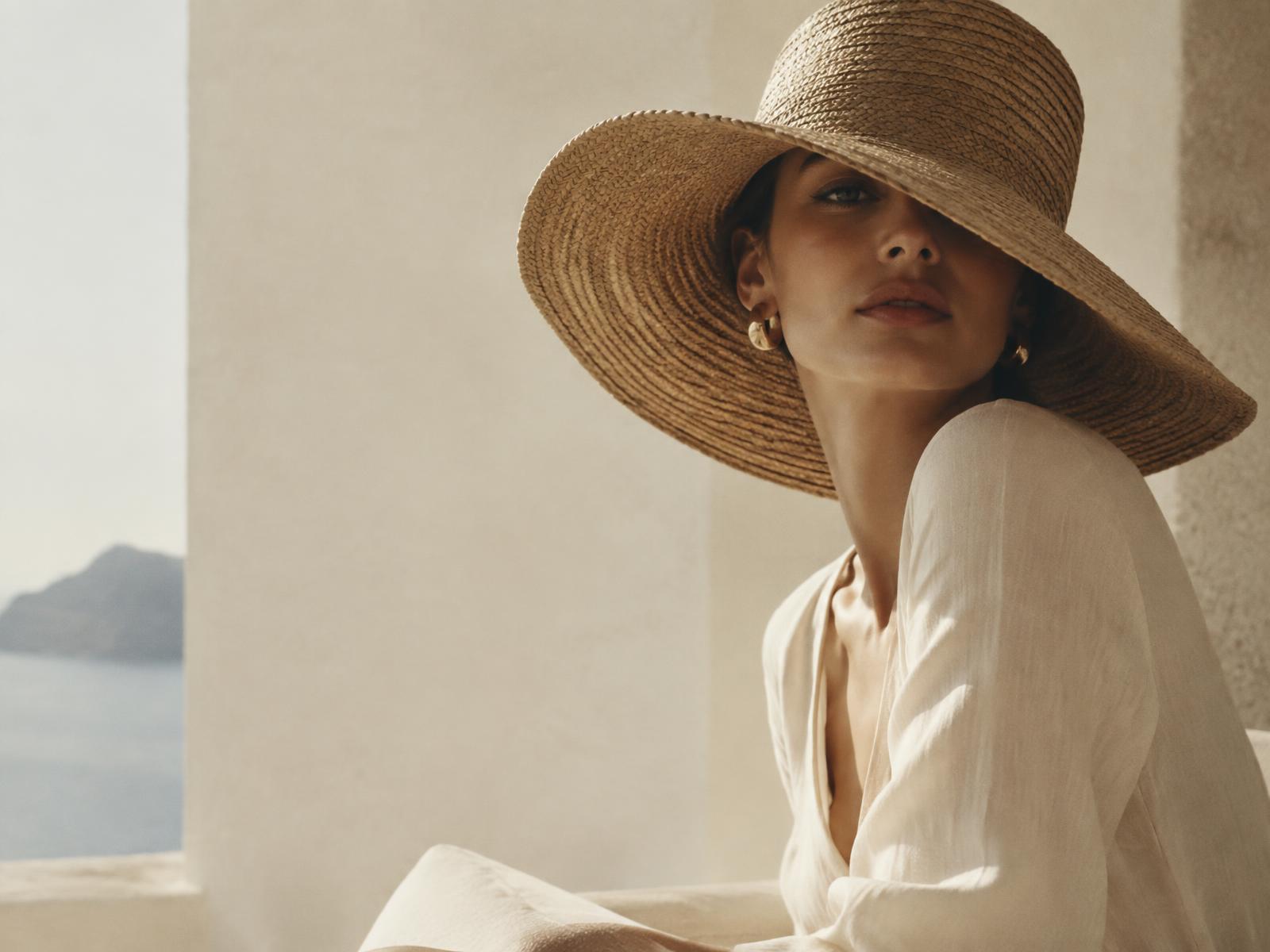 Femme portant un chapeau en paille Divine Headwear dans la lumière du matin